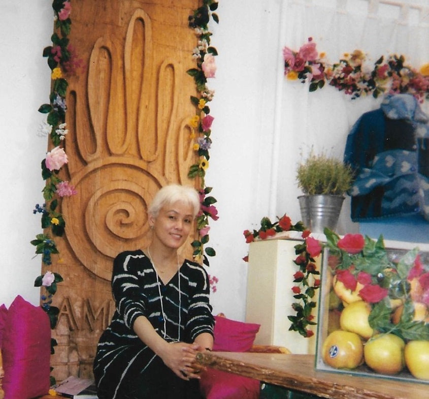 Yumiko Suzuki first Amano Designer sitting in front of Amano logo